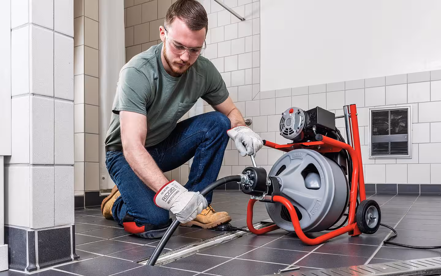 Drum-style drain snake machine used to clear a floor drain
